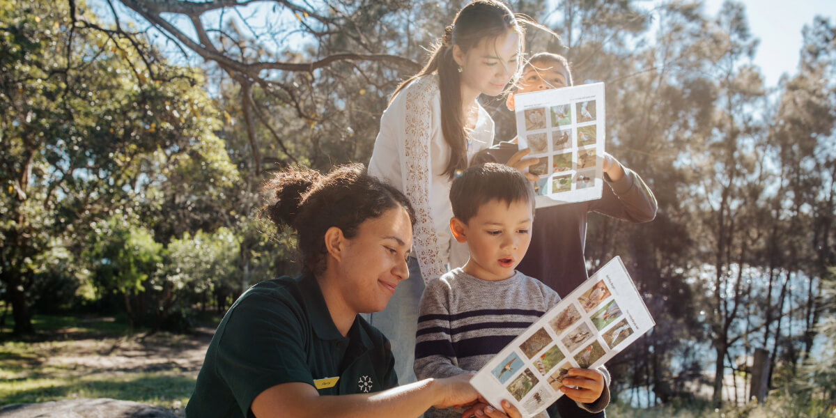 Two children and a facilitator engaging in a science activity outdoors