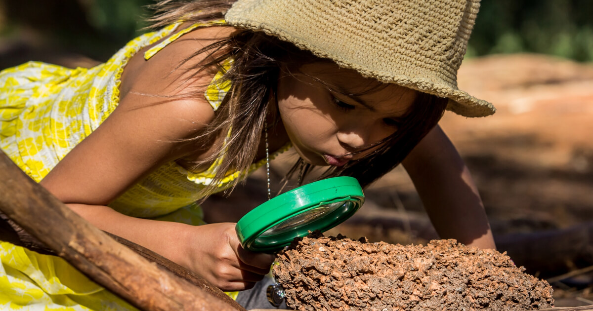 Young girl using a magnifying glass to look at a log