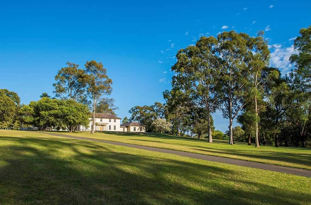 A large house located on a hill, with lush grass and trees, offering a beautiful landscape.